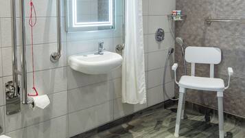 A bathroom with a white sink, a mirror, a shower, and a toilet.