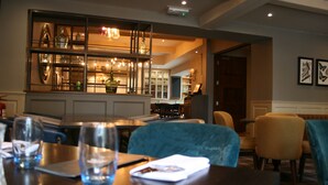 A dining area with a wooden table, chairs, and a bar area in the background. - Best Western Plus Angel Hotel (Chippenham)