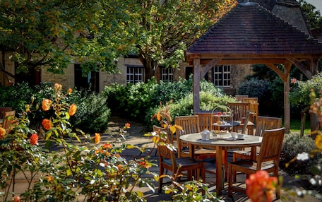 A garden with a gazebo, wooden tables, and chairs.