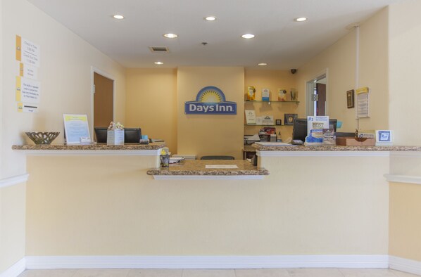 A reception desk with a Days Inn sign, a bulletin board, and a counter with various items. - Days Inn by Wyndham Shenandoah (Shenandoah)
