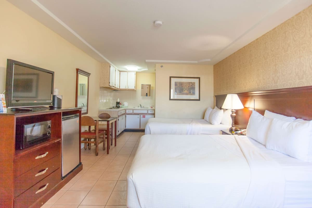 Une chambre d’hôtel avec deux lits, une kitchenette, une télévision et un coin repas.