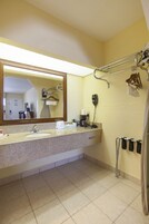 Un baño con lavamanos, espejo, toallero y secador de pelo.
