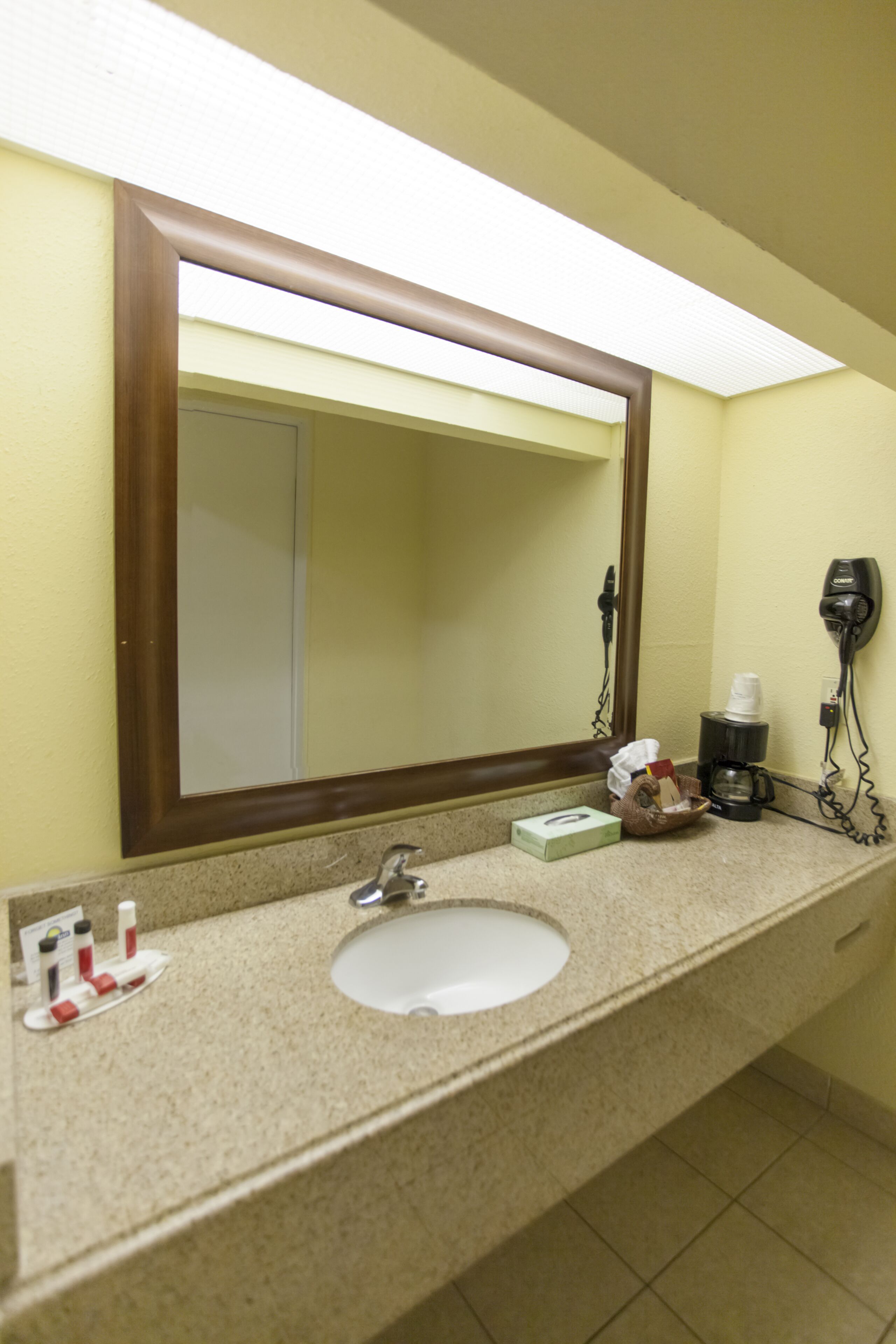 Un baño con lavamanos, espejo y artículos de aseo.