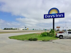 A Days Inn sign with a sun emblem, a parking lot, and a white truck. - Days Inn by Wyndham Shenandoah (Shenandoah)