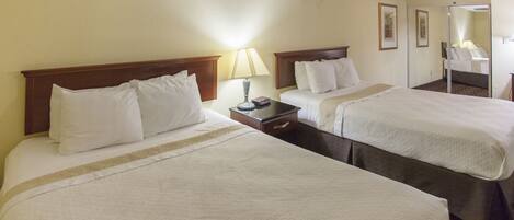 A hotel room with two beds, a nightstand, a lamp, and a ceiling fan.