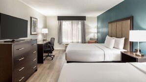 Ein Hotelzimmer mit Bett, Schreibtisch, Stuhl, Fernseher und Kommode.