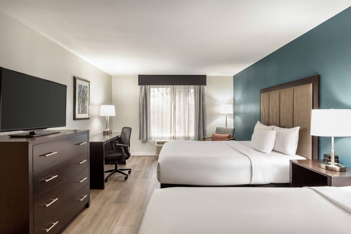 Ein Hotelzimmer mit Bett, Schreibtisch, Stuhl, Fernseher und Kommode.