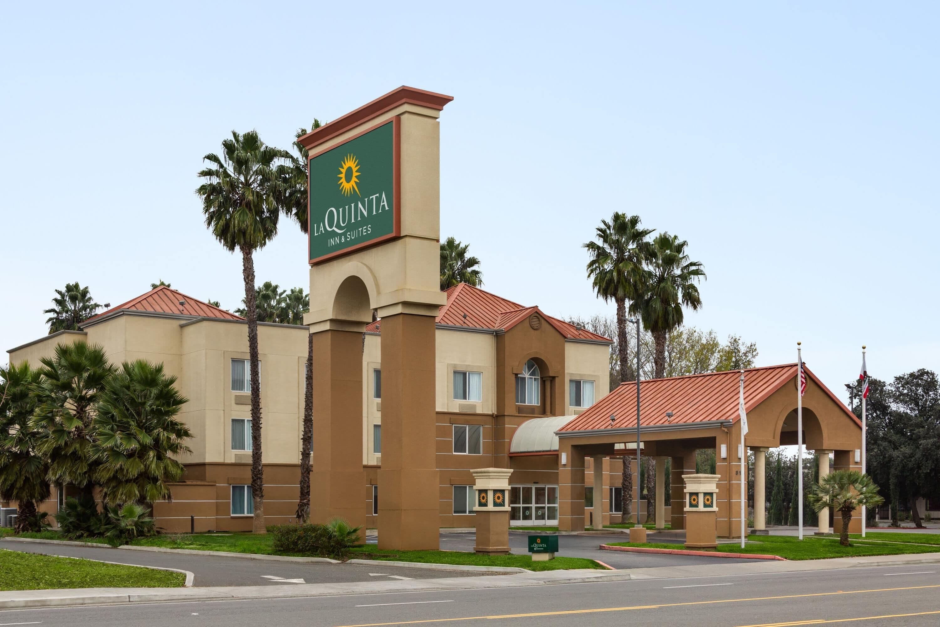 Edifici d'una La Quinta Inn & Suites amb façana beix, teulada de rajoles vermelles i palmeres.