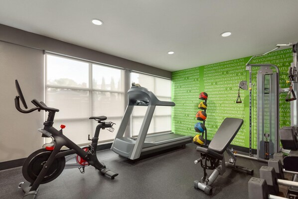 A gym with a treadmill, stationary bikes, and weight machines.