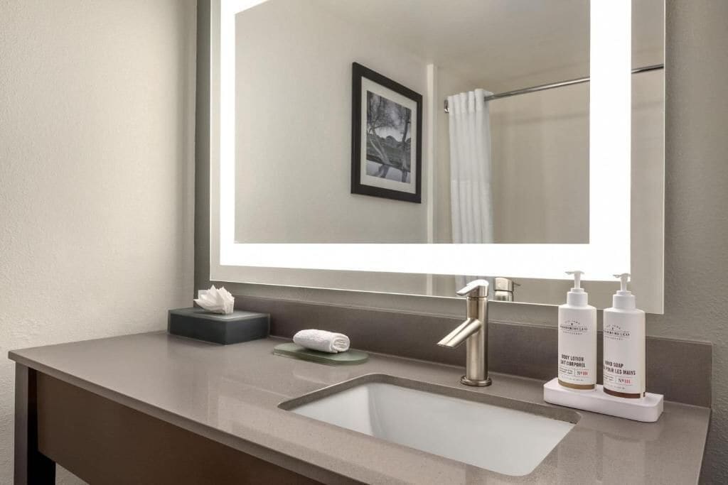A bathroom with a sink, mirror, and toiletries.