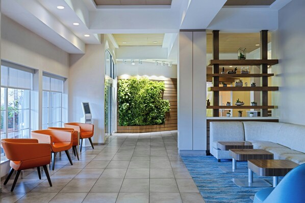 A modern lobby with a reception desk, seating area, and a green wall with plants. - EVEN Hotel Sarasota-Lakewood Ranch by IHG (Sarasota)