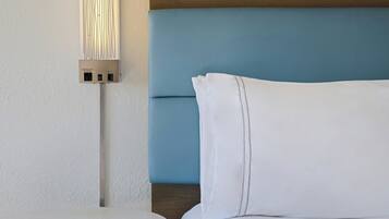 A hotel room with a round table, a bed with white linens, and a wall-mounted light fixture.