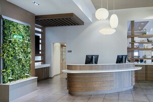 A reception area with a green wall, wooden reception desk, and pendant lighting.