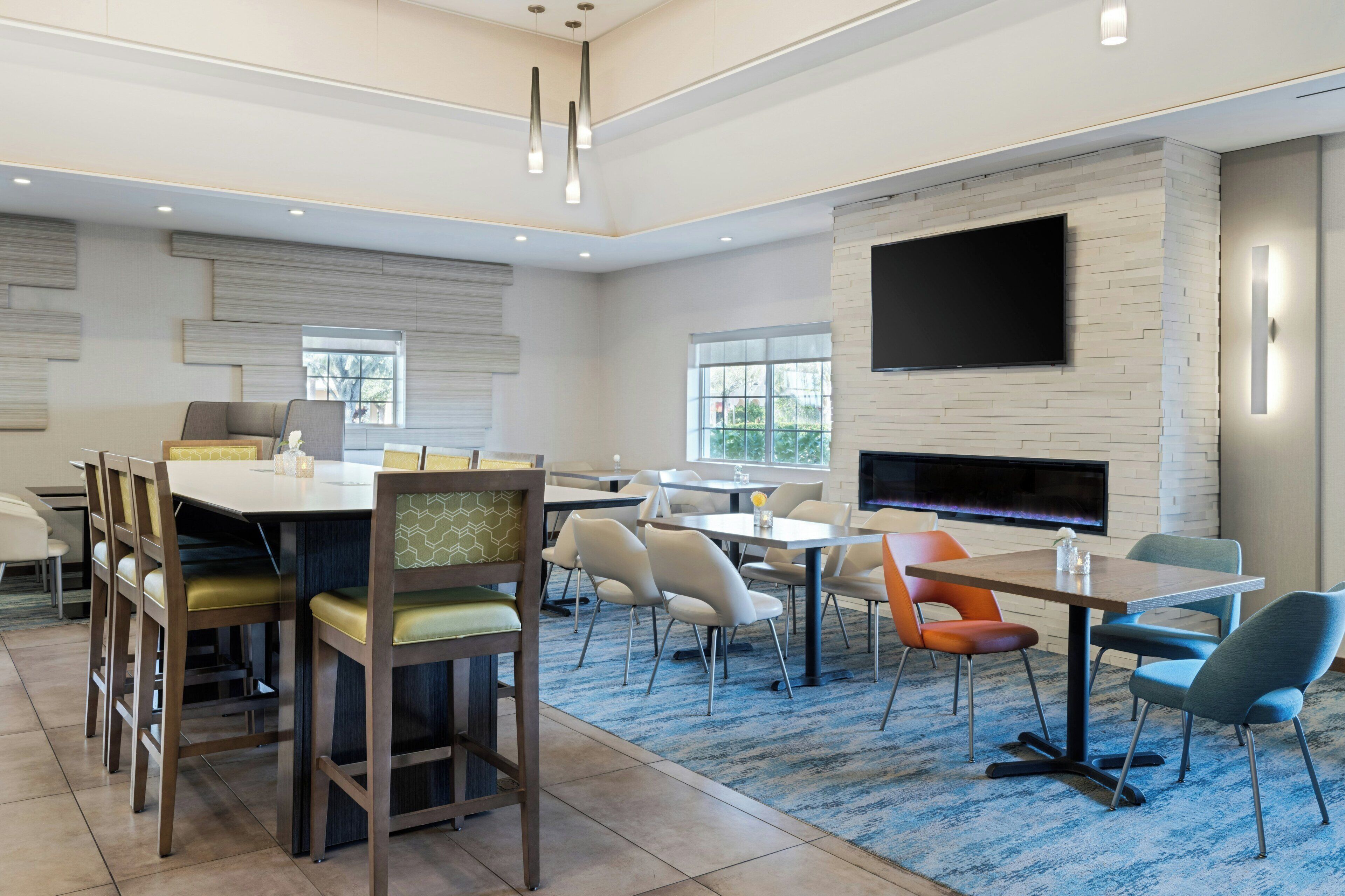 A modern conference room with a large table, chairs, a flat-screen TV, and a fireplace.
