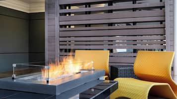 A modern outdoor seating area with a fire feature, a cushioned chair, and a wooden slatted wall.