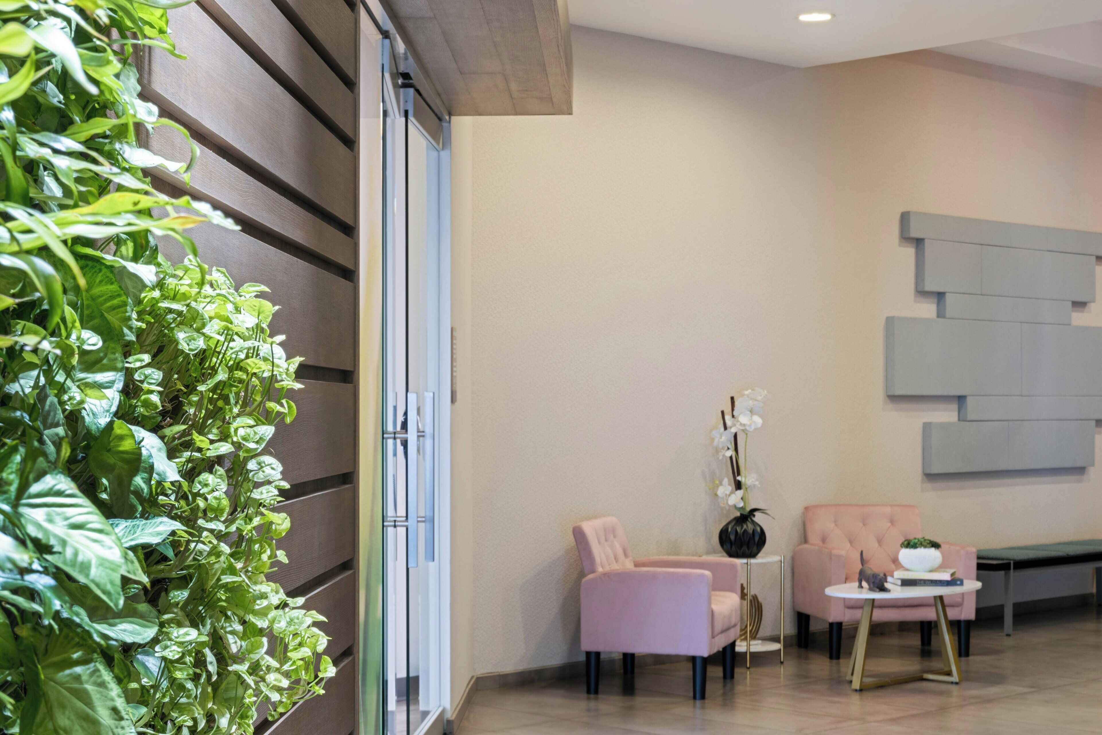 Un interior moderno con una zona de estar, una pared de plantas y una pieza decorativa en la pared.