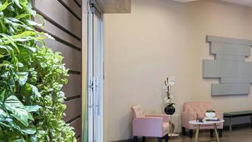 Un interior moderno con una zona de estar, una pared de plantas y una pieza decorativa en la pared.