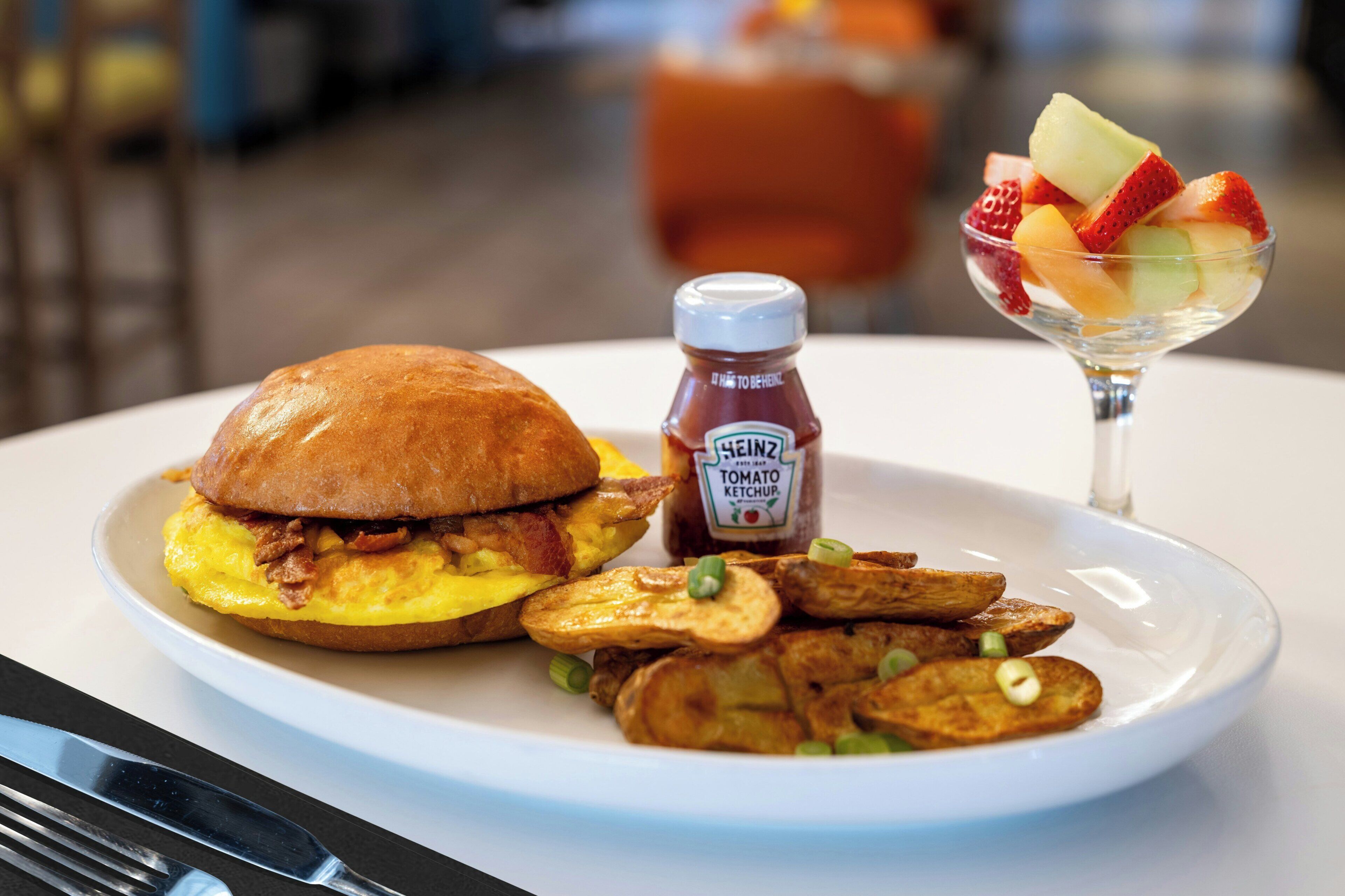 Un plato con un sándwich, papas fritas y una bebida de frutas.