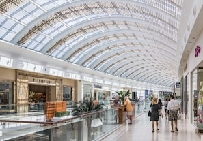 Un centro comercial moderno con un techo de vidrio alto y varios niveles.