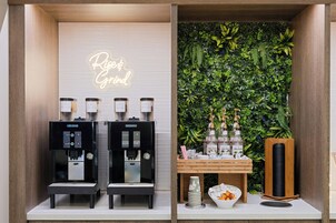 Una estación de café con dos máquinas de espresso, un letrero de neón y una pared cubierta de vegetación.