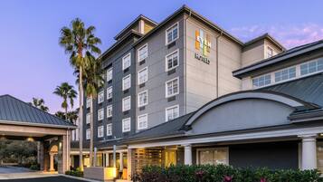 A multi-story hotel building with a modern architectural design, featuring a prominent sign for 'Even Hotels' and a covered entrance area.