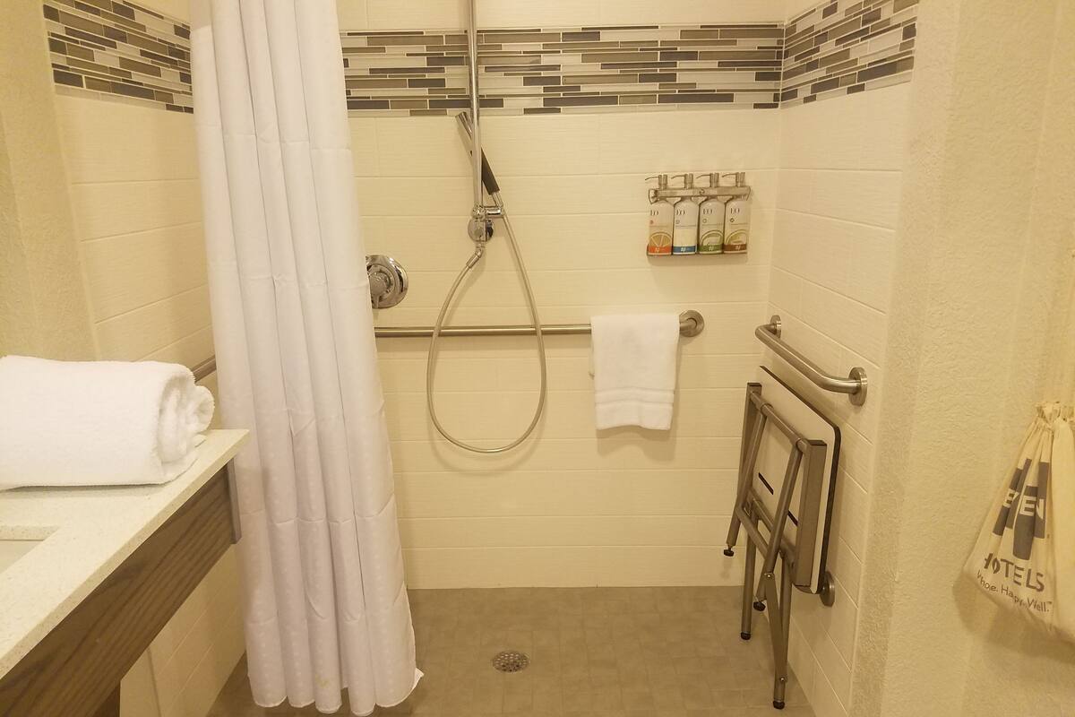 Baño con ducha, toallero y secador de manos.