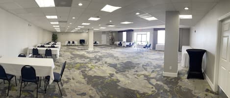Un salón de conferencias con mesas, sillas y piso alfombrado.