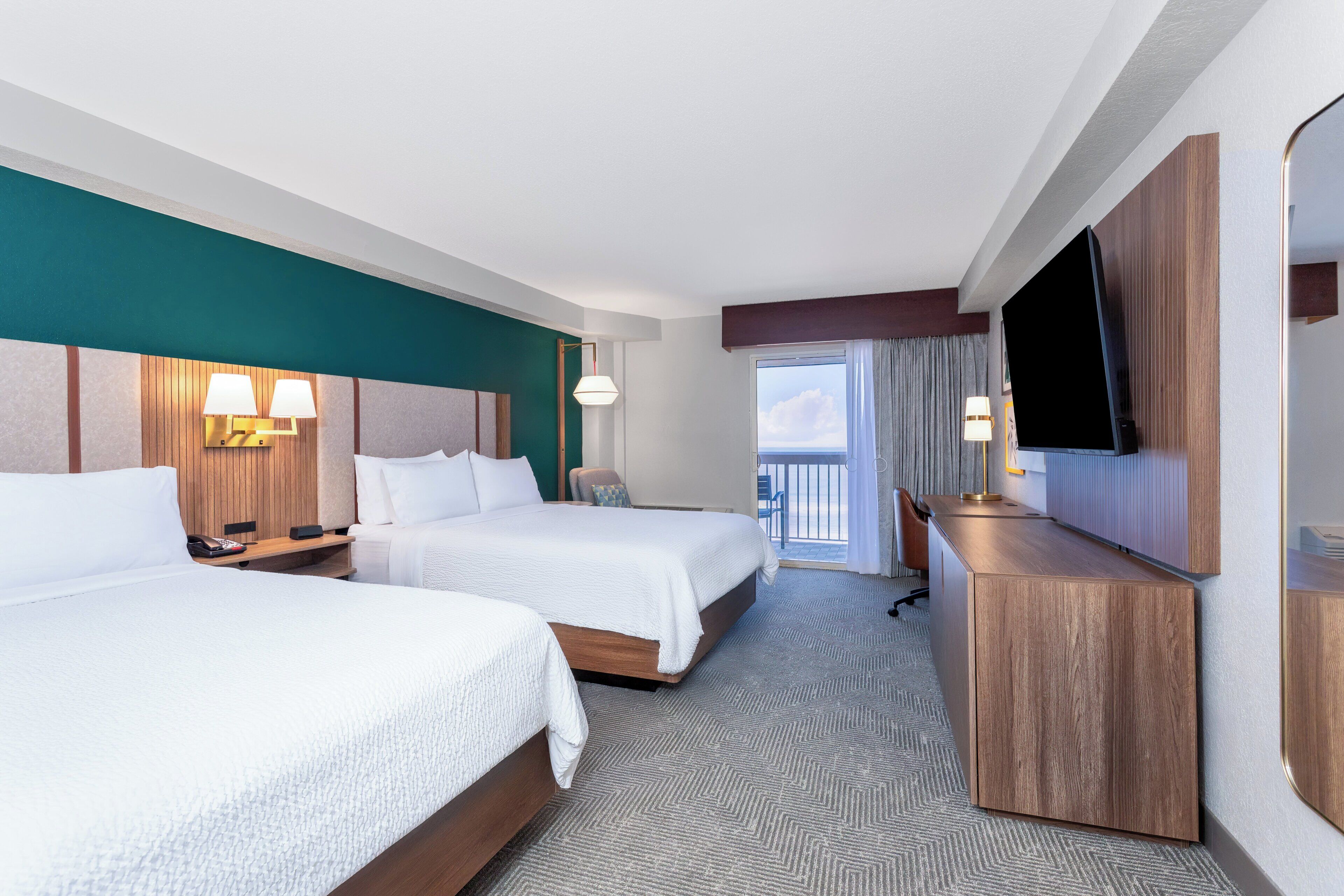 Une chambre d’hôtel avec deux lits, une télévision, un bureau et une vue sur le ciel.