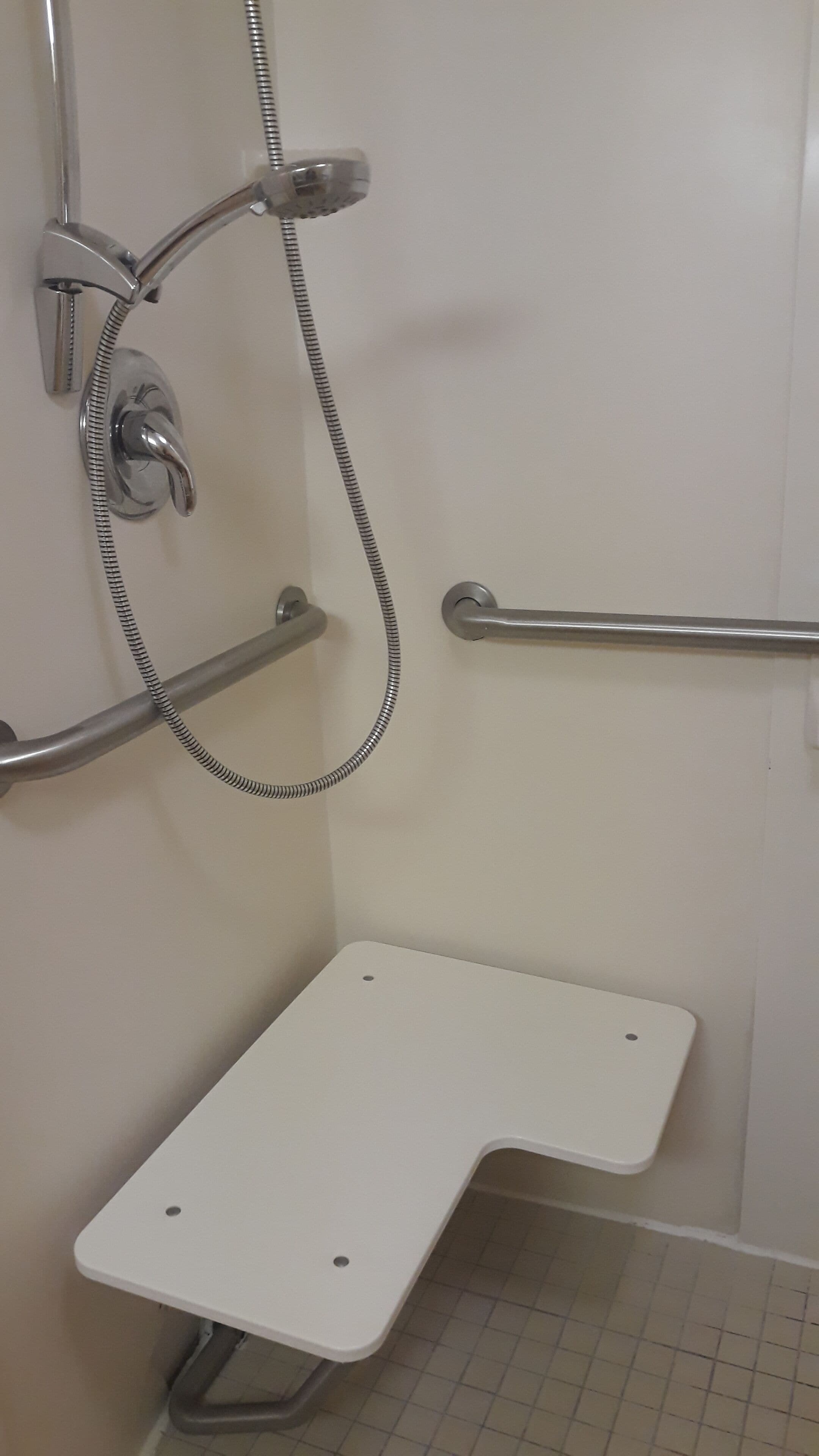 Et bruseområde med gelænder, brusehoved og en hvid vask.