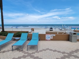 Un área de descanso junto a la playa con sillones azules y vistas al océano.