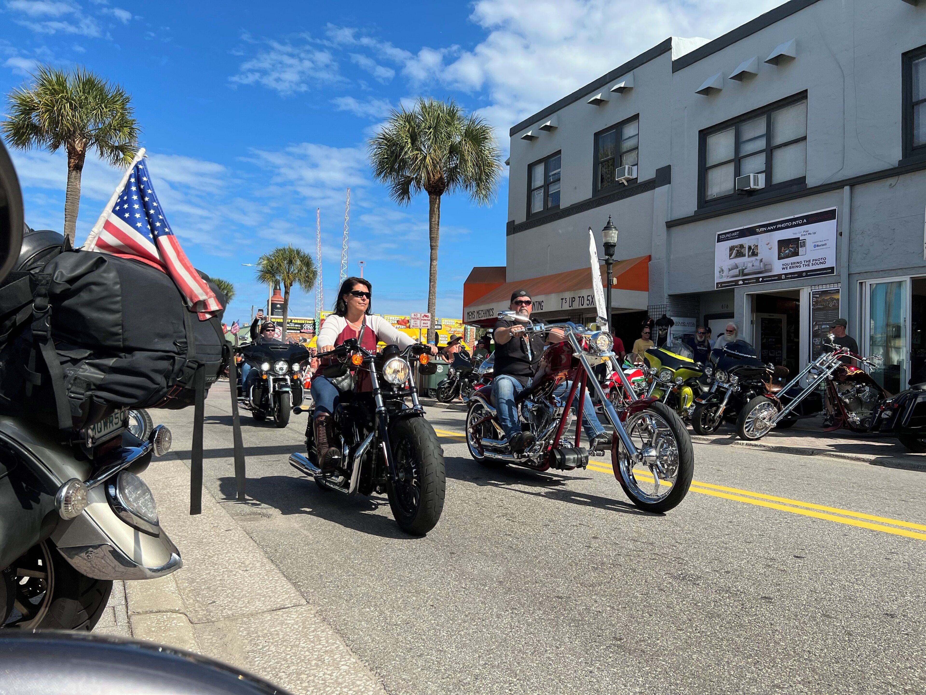 A street lined with parked motorcycles and palm trees.