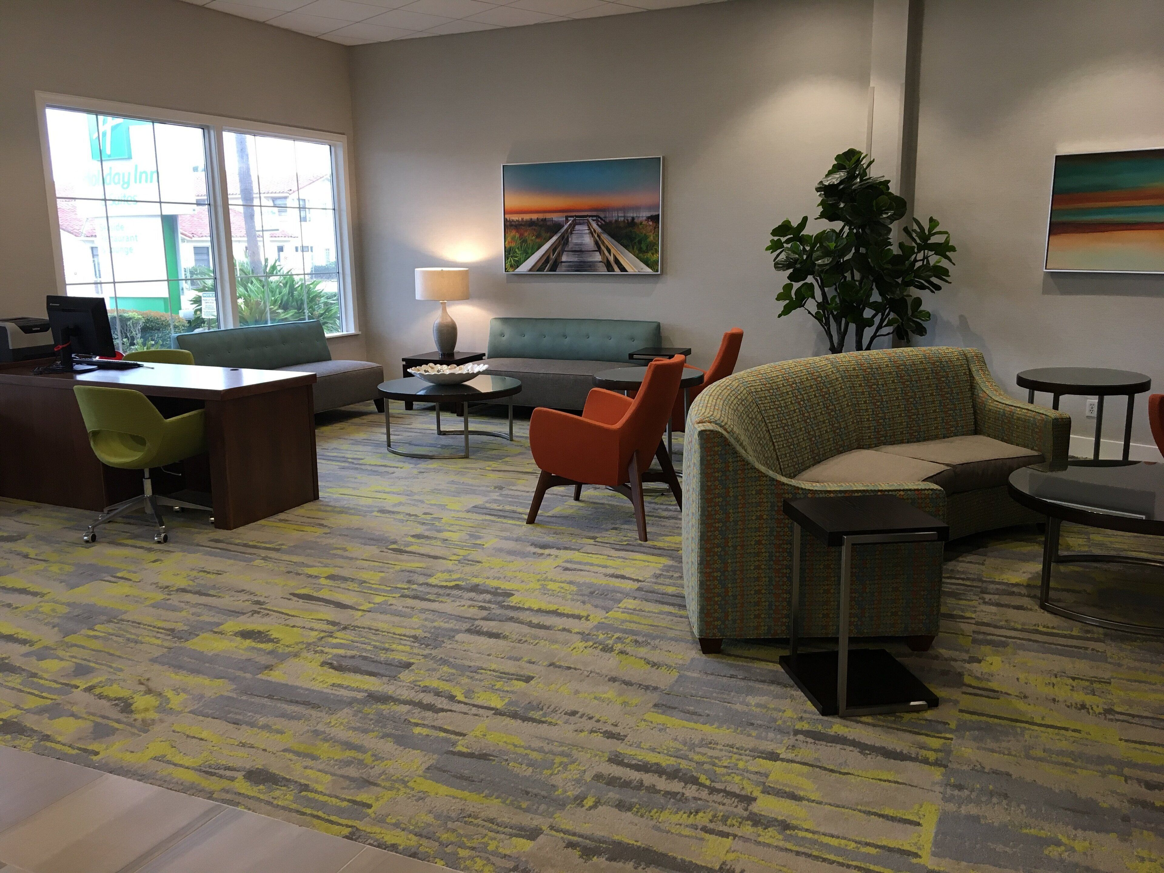A hotel lobby with a reception desk, seating area, and a large window.