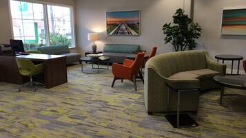 A hotel lobby with a reception desk, seating area, and a large window.