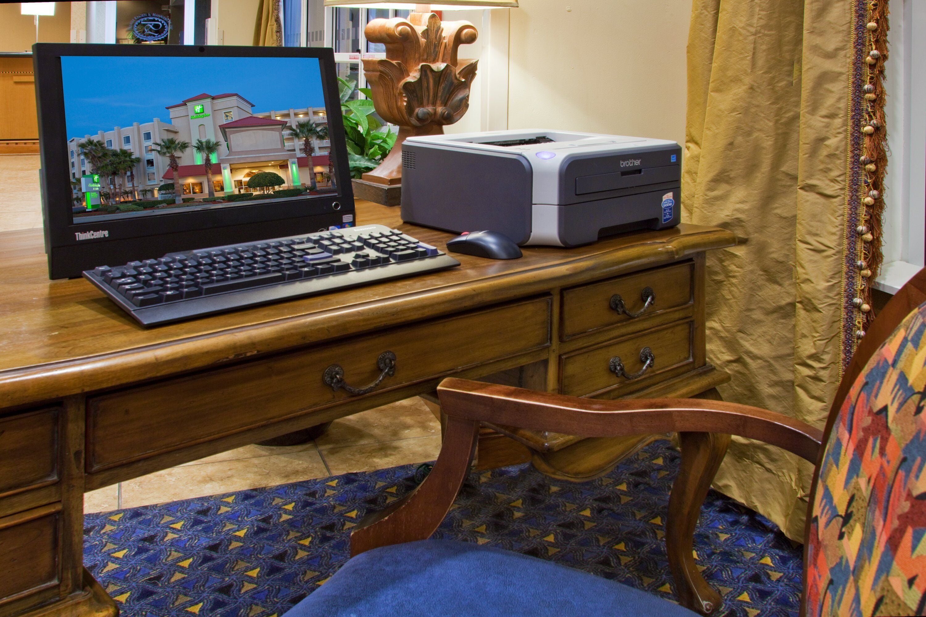 Un bureau en bois avec un ordinateur de bureau, une imprimante et un vase décoratif.