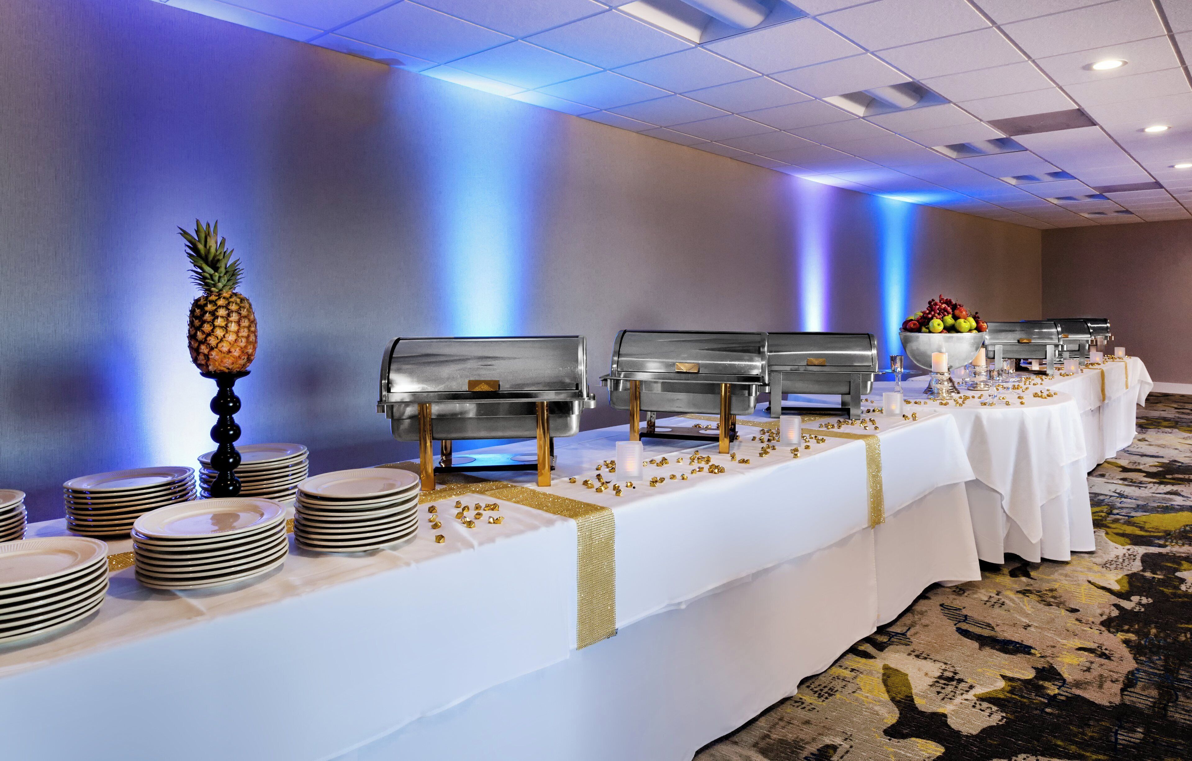 A buffet setup with multiple serving stations, plates, and a pineapple centerpiece.