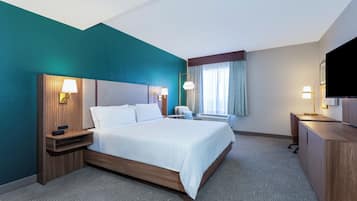 A hotel room with a bed, bedside tables, a desk, and a television.