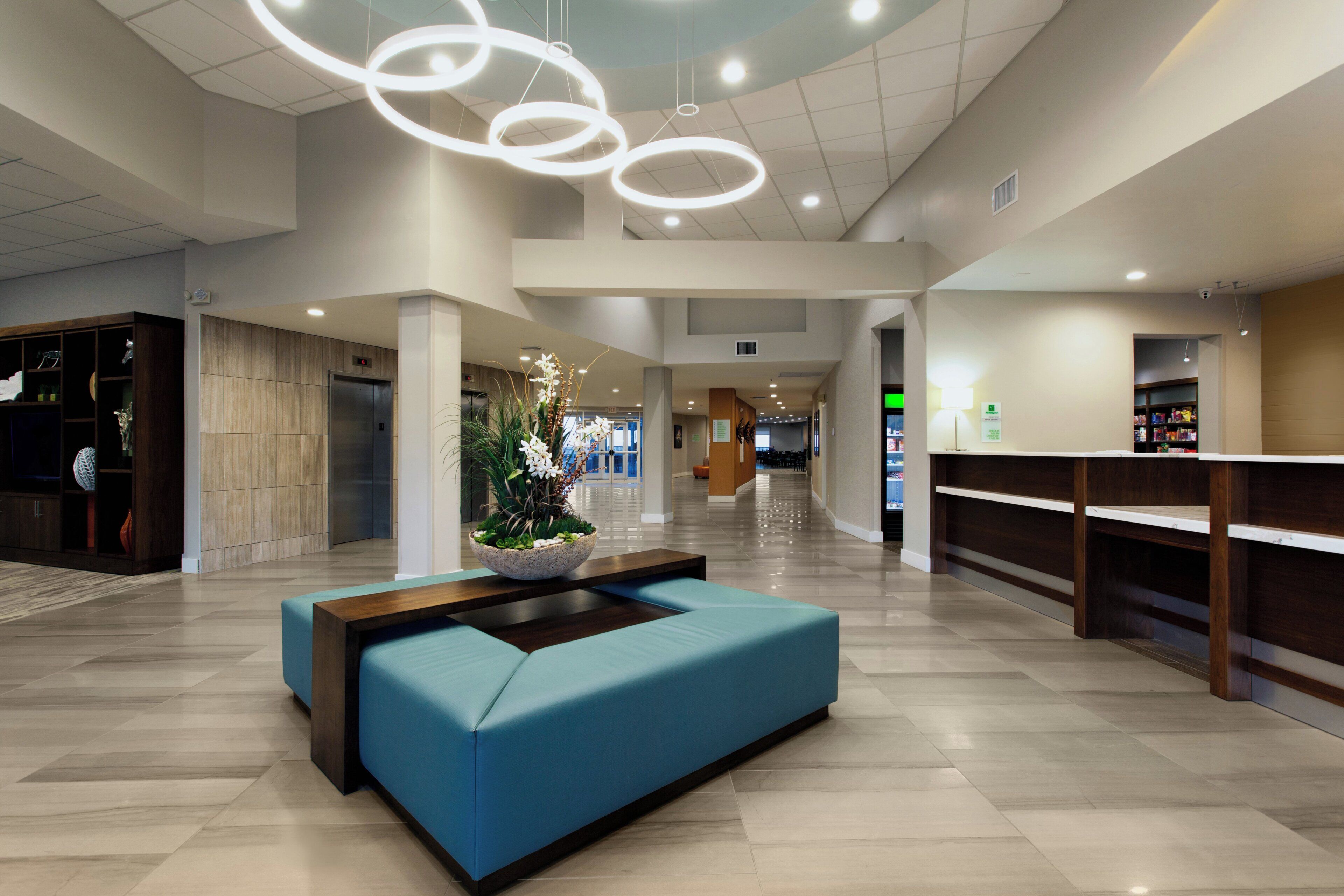 A spacious lobby with a blue seating area, a reception desk, and a modern ceiling design.