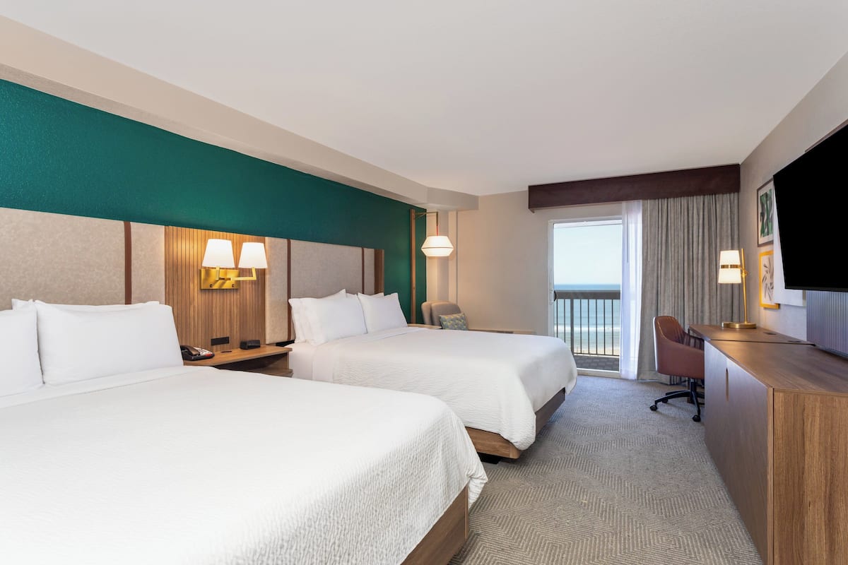 Een hotelkamer met twee bedden, een bureau, een stoel en een televisie.