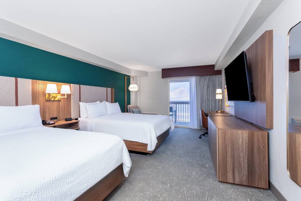 Een hotelkamer met twee bedden, een televisie, een bureau en uitzicht op de lucht.