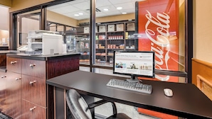 Un mostrador de recepción de hotel con una computadora, un teléfono y una vitrina de vidrio que contiene varios objetos.
