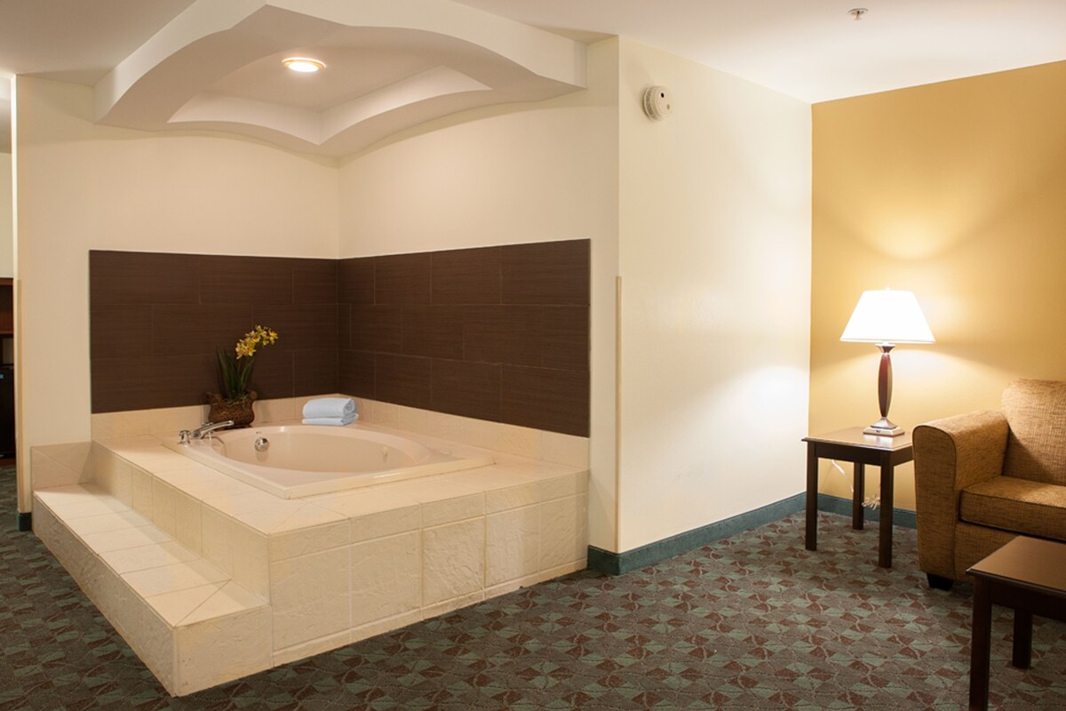 Un baño con una bañera, una mesita con una lámpara y un sofá.