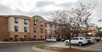 Un hotel Holiday Inn Express con un estacionamiento y un árbol en la entrada.