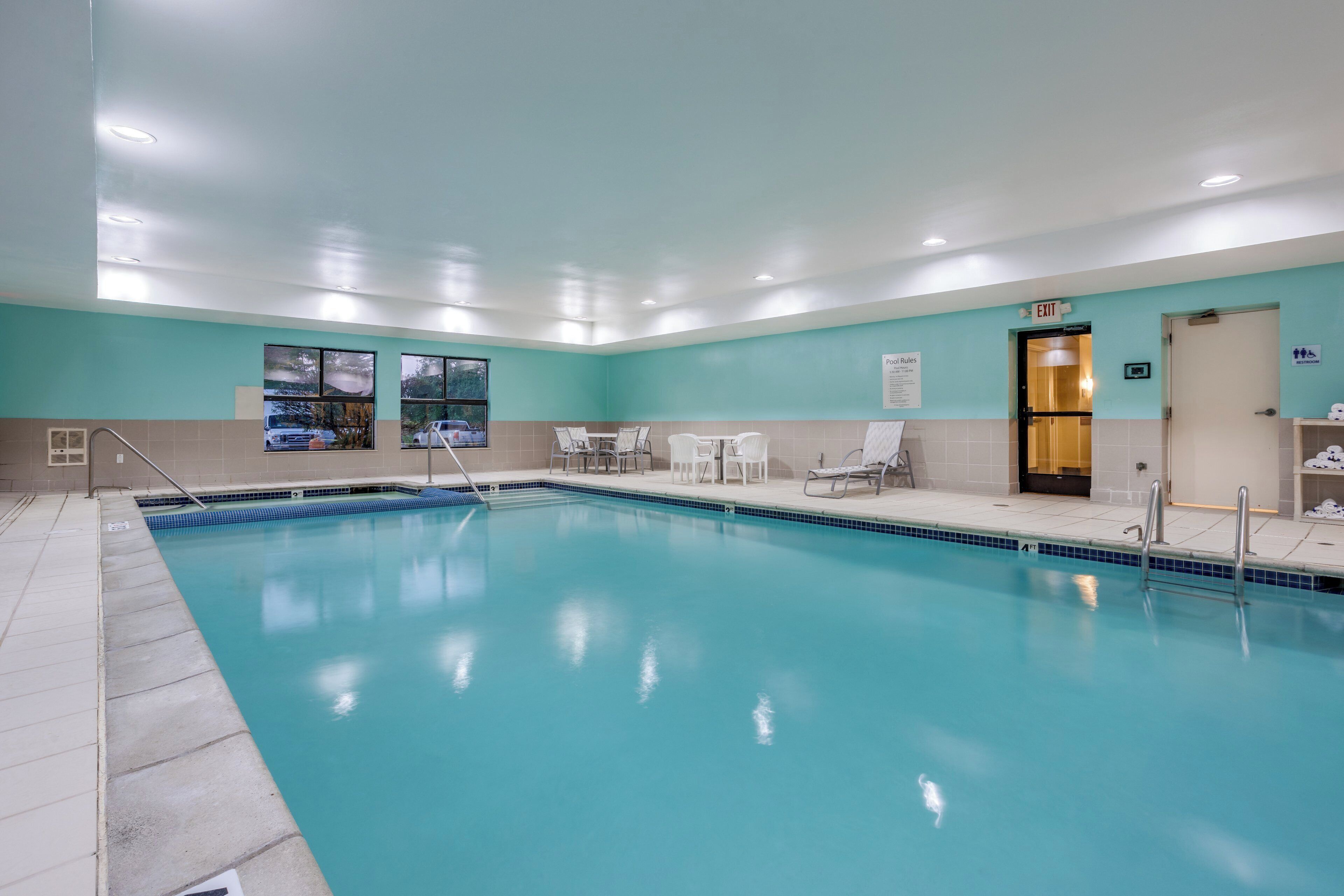 A swimming pool with lounge chairs and a door marked 'EXIT'.