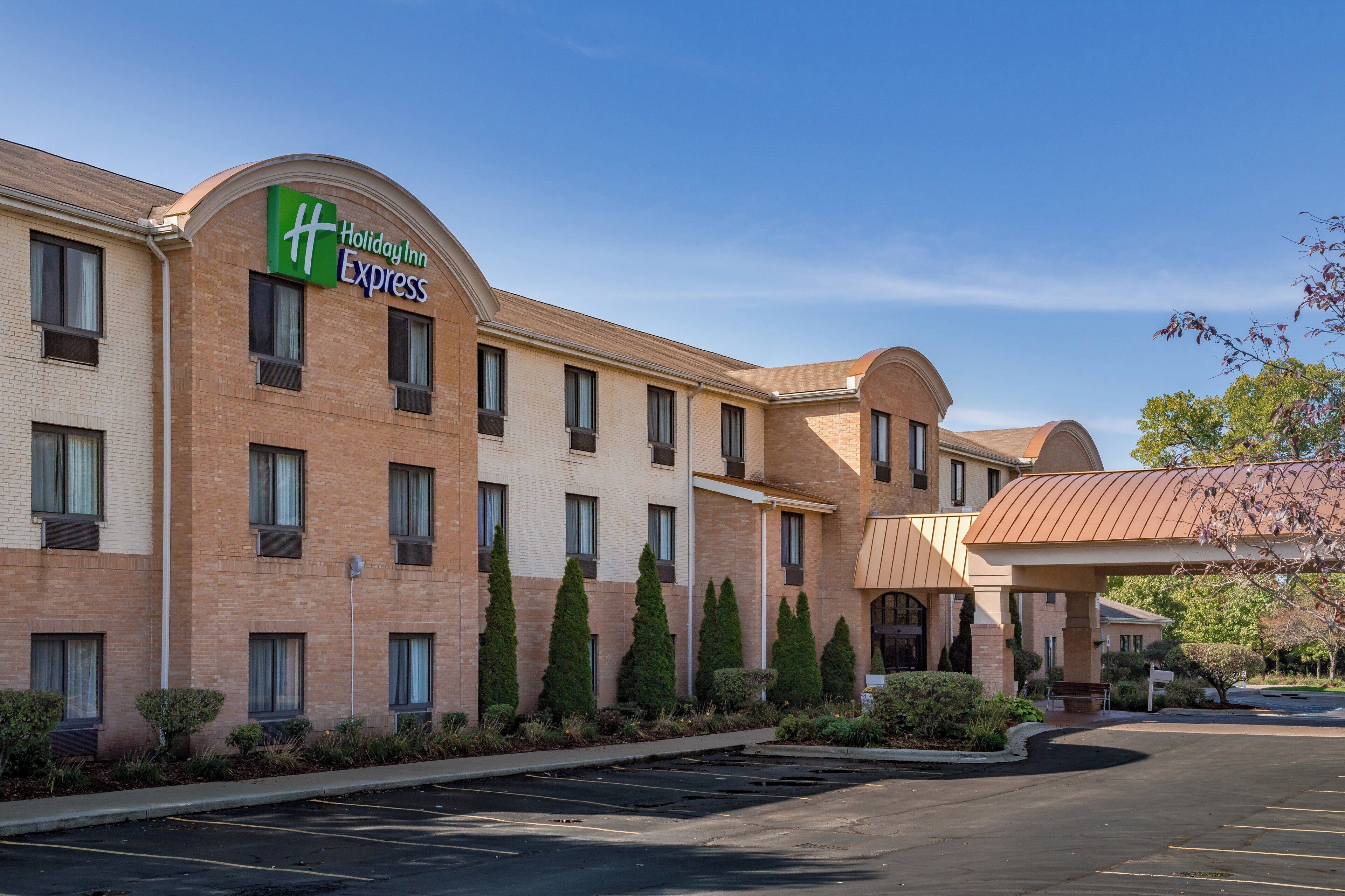 Edificio Holiday Inn Express con fachada de ladrillo, varias ventanas y un estacionamiento.