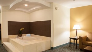 A modern bathroom with a freestanding bathtub, a small table with a lamp, and a sofa. - Holiday Inn Express Hotel & Suites Canton by IHG (Canton)