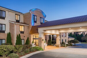 A hotel with a brick facade, a covered entrance, and a parking area.