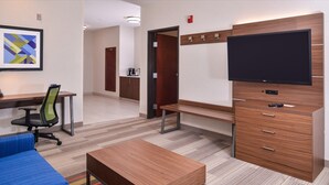 A modern hotel room with a flat-screen TV, wooden furniture, a desk, and a colorful rug. - Holiday Inn Express & Suites Albany by IHG (Albany)
