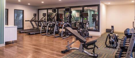 Une salle de sport équipée de tapis de course, de vélos elliptiques et de matériel de musculation.