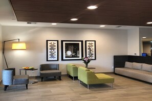 A modern living room with a sofa, two armchairs, a small table with fruit, and a floor lamp. - Holiday Inn Express & Suites Albany by IHG (Albany)