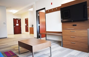 A hotel lobby with a wooden bench, a flat-screen TV, a coat rack, and a door. - Holiday Inn Express & Suites Albany by IHG (Albany)